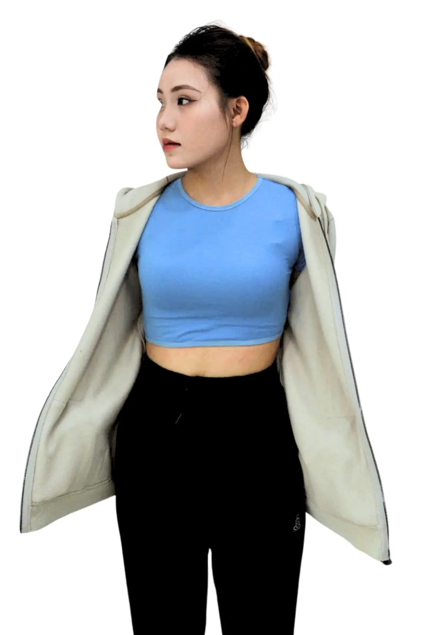 Woman in blue crop top and black pants with a light jacket draped over shoulders.