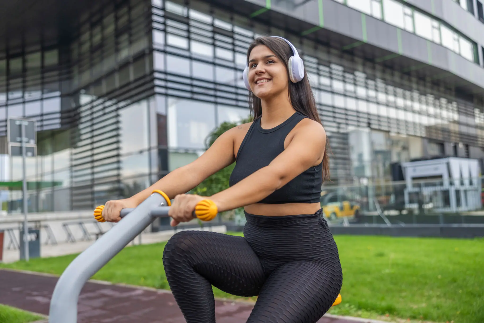 Woman with headphones exercising on outdoor bike