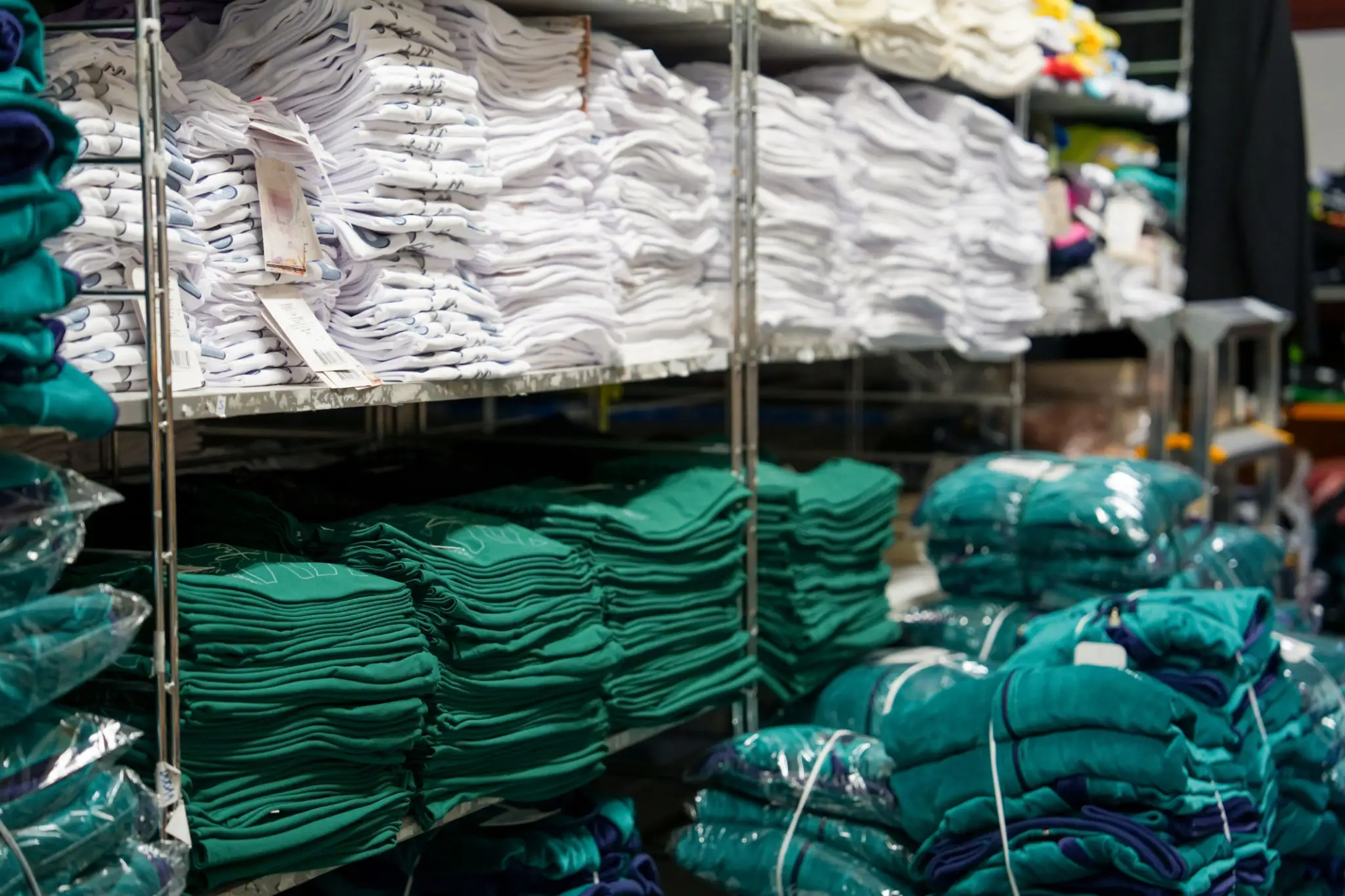 Shelves of folded green and white shirts