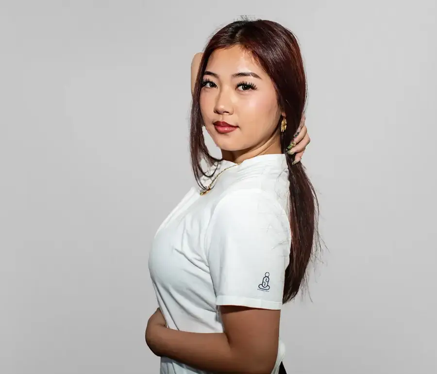 Young woman with red hair in a white shirt posing against a plain background.